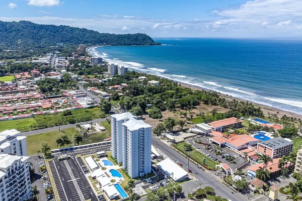 Luftaufnahme des Strands von Jacó und der Pazifikküste mit bewaldeten Hügeln, Costa Rica